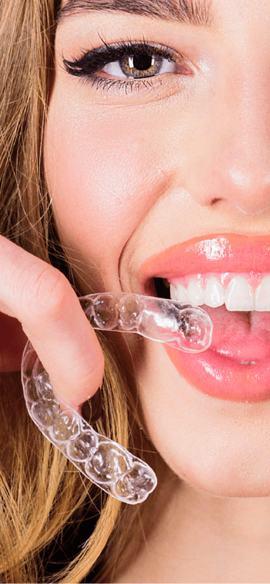 Patient smiling while holding a clear aligner.